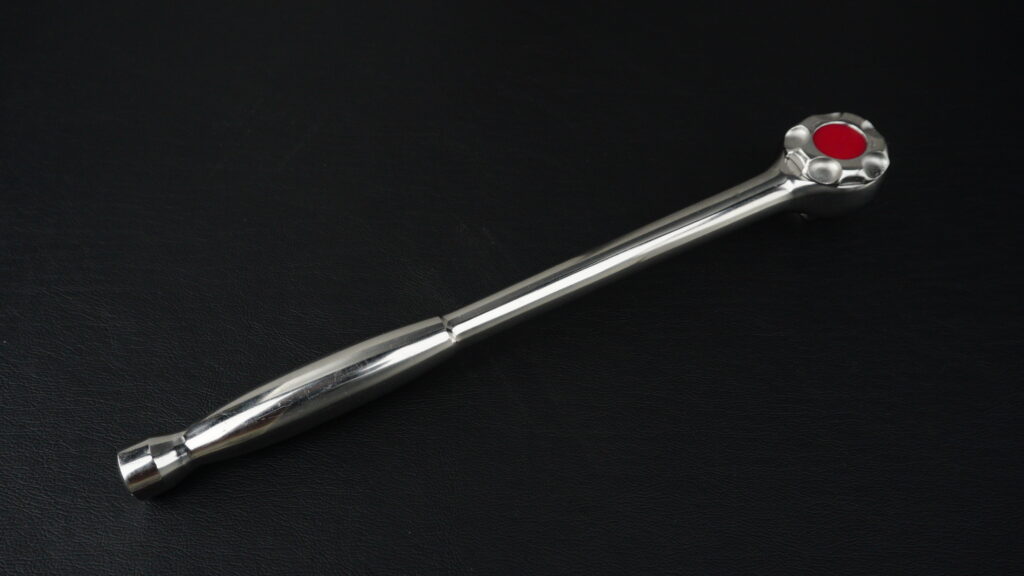 黒い背景に置かれたTONE（トネ）製ステンレスラチェットハンドル SRH31 の全体写真。赤い切替ダイヤルが特徴的。