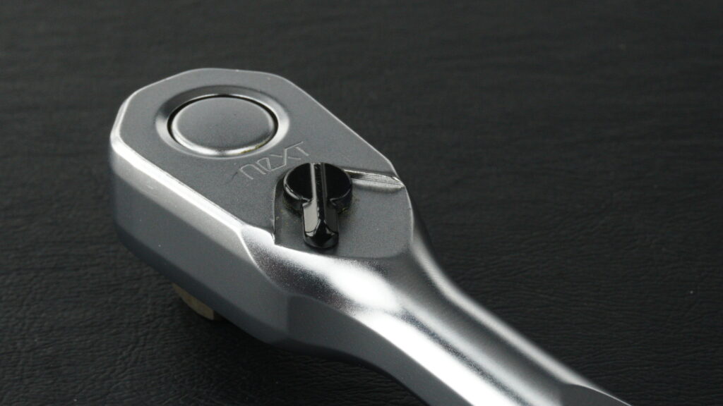 KTC nepros neXT NBR390Xラチェットハンドルのヘッド表面拡大写真。ショットピーニング処理によるマットな質感と、プッシュボタンや切り替えレバーのディテール。