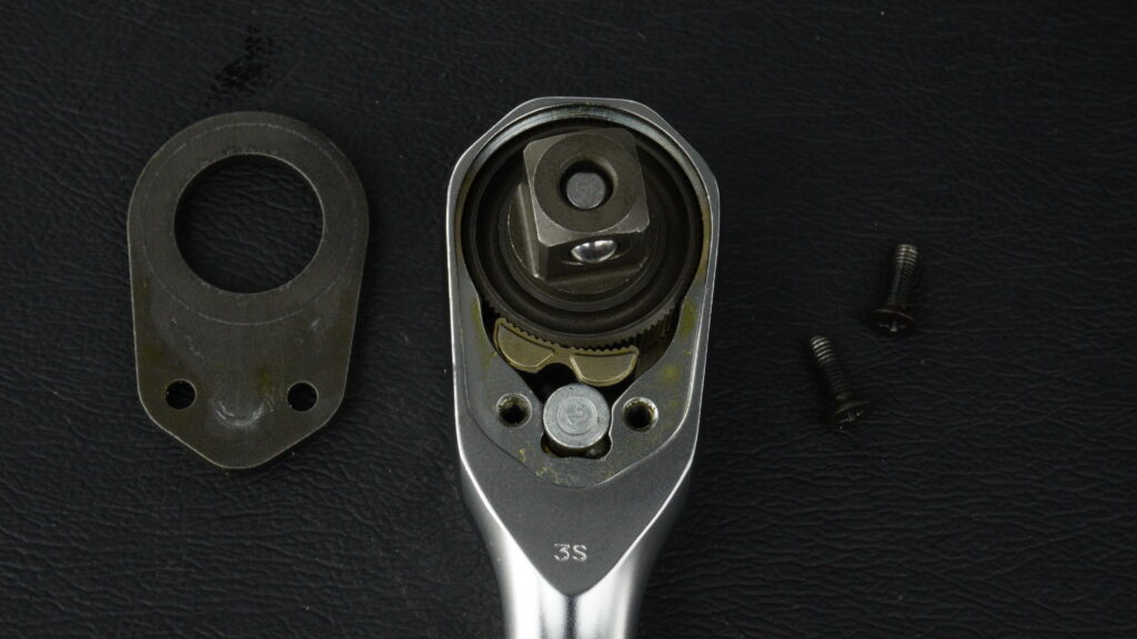 KTC nepros neXT NBR390Xラチェットハンドルのヘッド部分解写真。外されたカバープレート、2本の固定ネジ、および内部のギア機構。